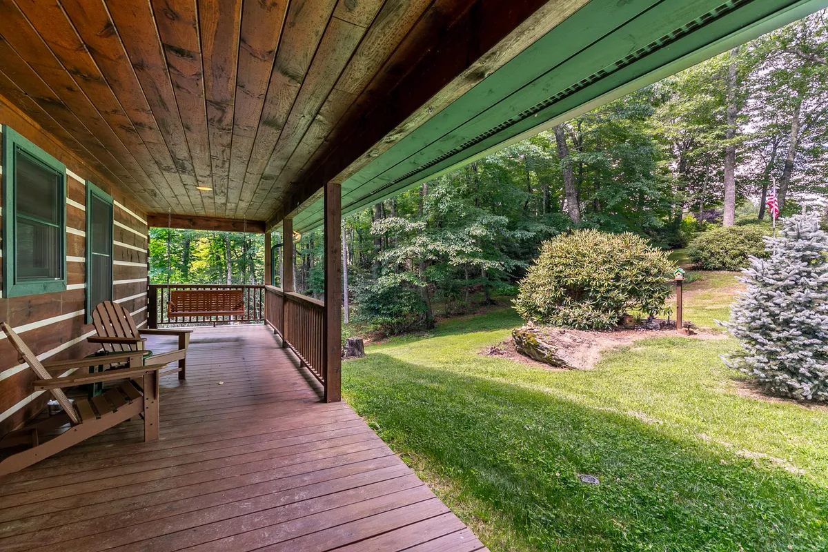 A wooden deck with a cozy swing bench overlooking lush greenery and natural rock formations. The scene evokes relaxation and conversation, ideal for unwinding after a day in town or at the park, and hints at opportunities for hosting small outdoor gatherings.
