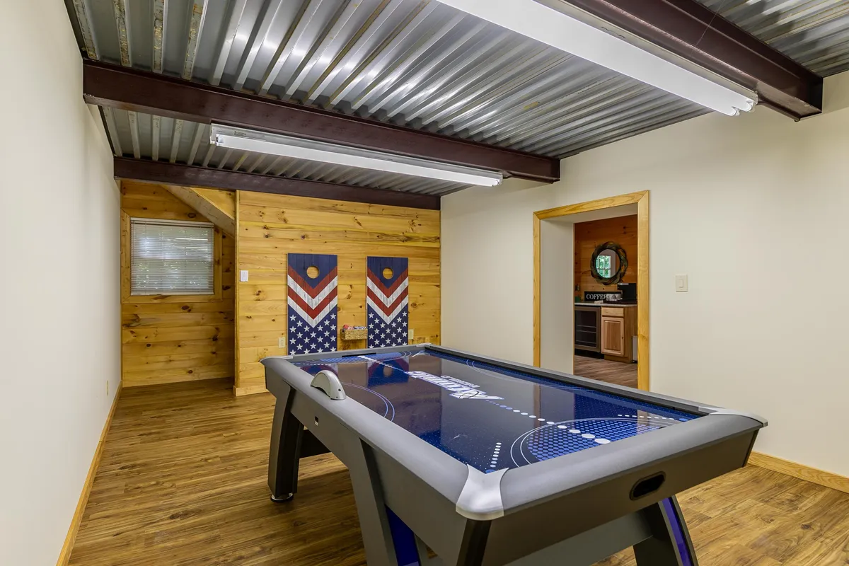 A lively interior game room featuring an air hockey table, wooden wall accents, and decorative panels, crafted for friendly family tournaments and entertaining evenings indoors.