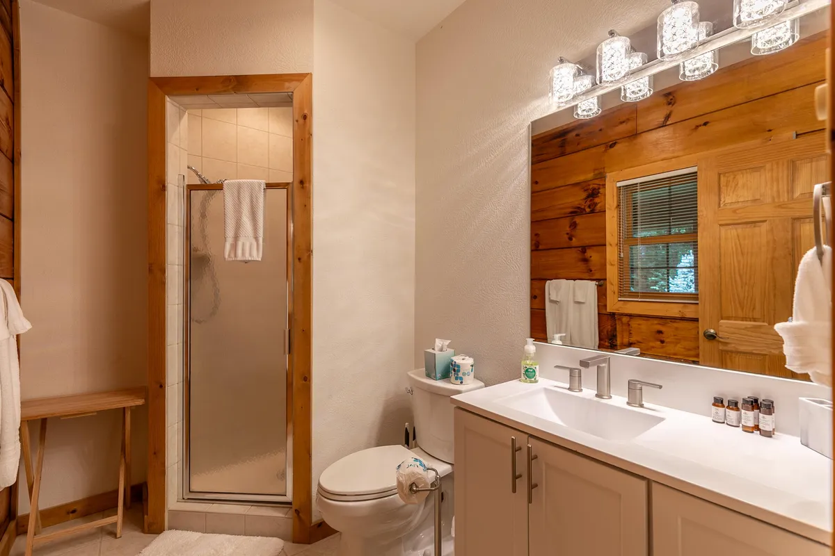A modern bathroom with a sleek sink, wooden accents, a shower area, and a stylish mirror. The layout is inviting and tranquil, offering a spa-like experience for personal relaxation and refreshment.