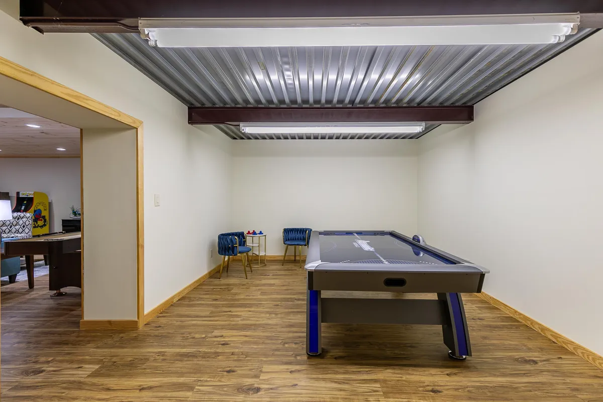 A dedicated corner of the game area featuring an air hockey table and a small seating area, designed for friendly matches and informal gatherings. The space looks bright and inviting, ideal for spirited gameplay.