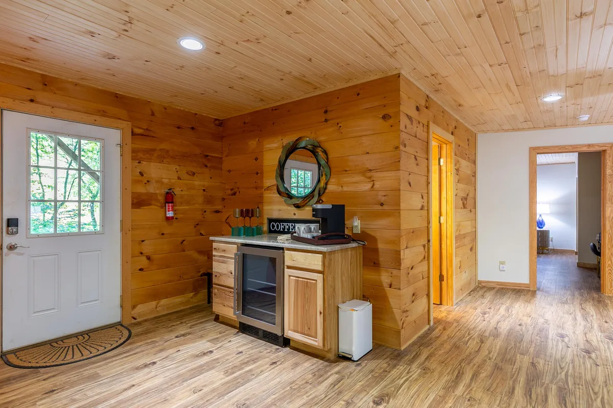 A cozy nook with a coffee station, wooden paneling, a welcoming front door, and a mirror. The setup invites guests to enjoy refreshments and relax with a cup of coffee between games or movie moments.